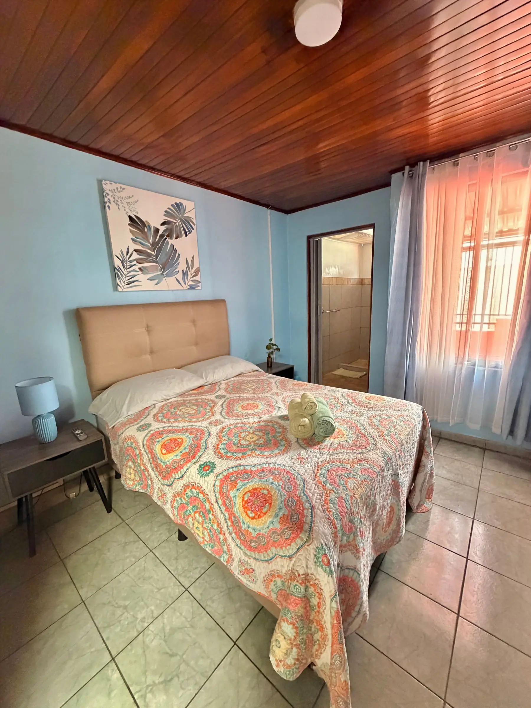 Habitación Oasis #2, con ventana a la calle y luz natural, cama queen y pared celeste en Casa Oasis, Alajuela