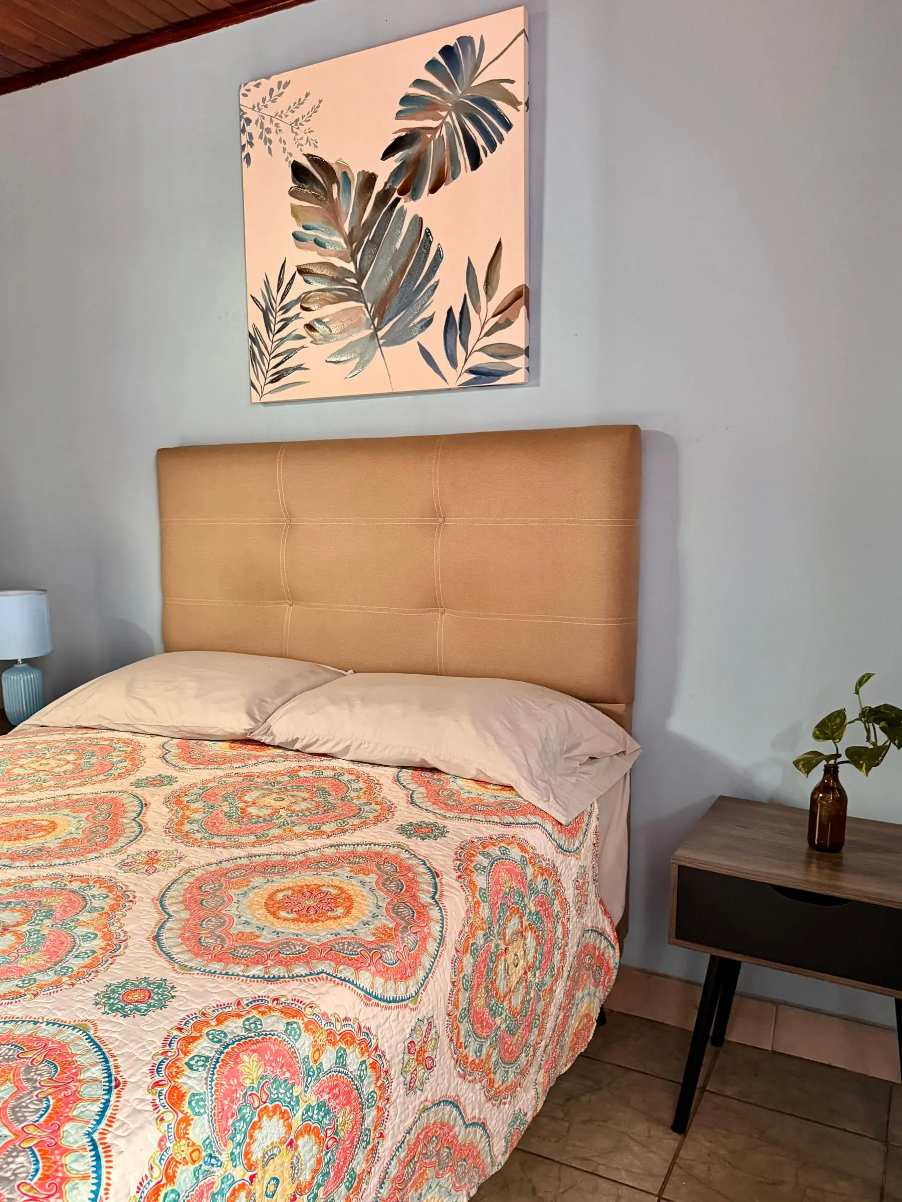 Cama queen con cabecera tapizada y mesa de noche en la Habitación Oasis #2