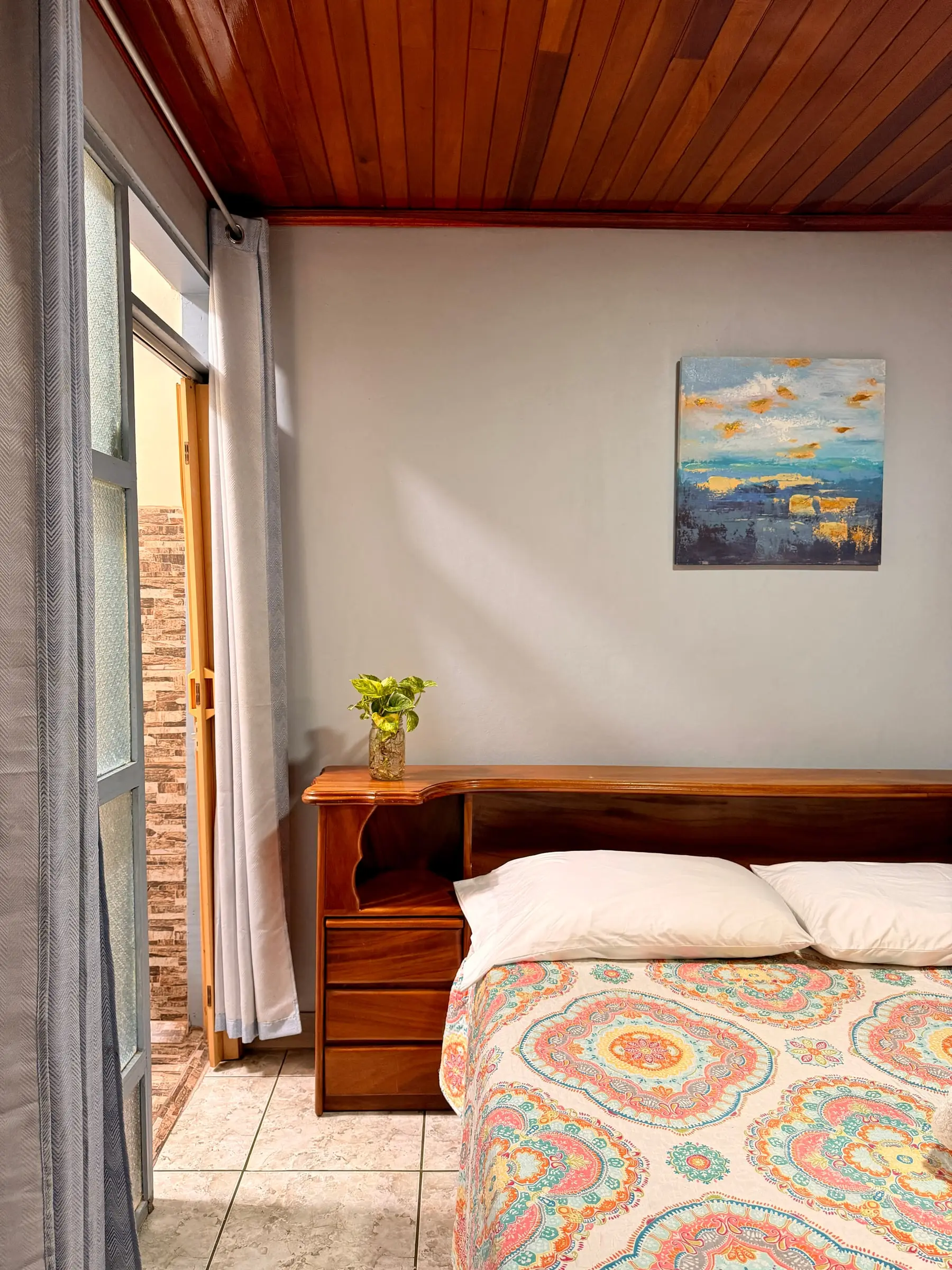 Cama queen con cabecera de madera en la Habitación Oasis #1