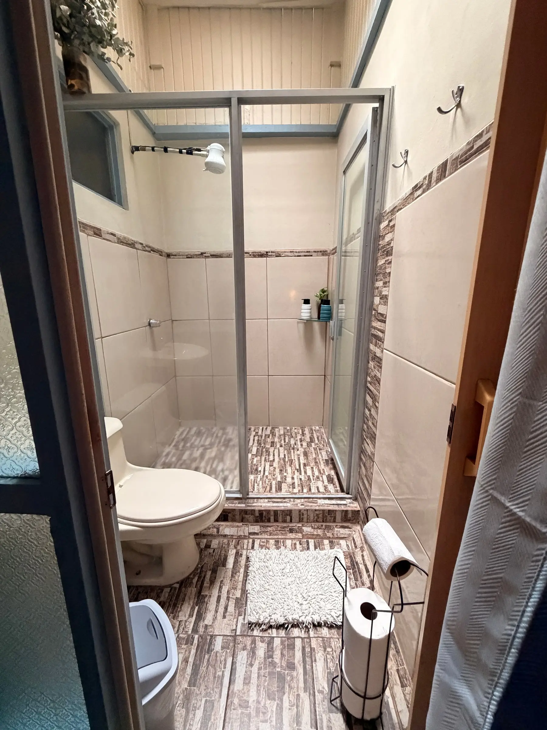 Ducha con puerta de vidrio en el baño privado de la Habitación Oasis #1